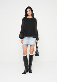 Μαύρο διαφανές τοπ με μακριά μανίκια, μίνι φούστα από ανοιχτό μπλε τζιν, μαύρες μπότες μέχρι το γόνατο και μικρή μαύρη τσάντα. Απλός σχεδιασμός και μοντέρνο στυλ.