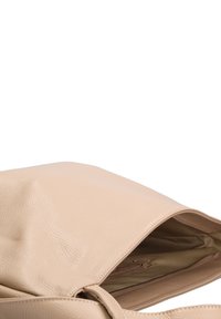 Beige leren tote bag met een gestructureerde afwerking, ritssluiting en een ruime binnenkant. Binnenin bevindt zich een zijvak.