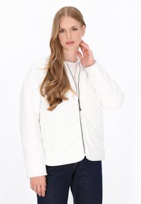 Weiß gesteppte Jacke mit einem Frontreißverschluss, langen Ärmeln und einem lässigen Schnitt, kombiniert mit einem einfachen T-Shirt und dunklen Jeans. Glatte Textur.