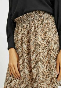 Brun mönstrad kjol med elastisk midja, med abstrakta mönster i ljusa och mörka nyanser. Mjuk, flödande tygtextur.