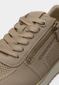 Baskets beige en tissu texturé, lacets proéminents et fermeture éclair latérale. Livrées avec un logo « TOM TAILOR » et une semelle en caoutchouc lisse.