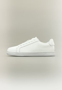 Basket blanc basse avec lacets, dessus lisse et semelle en caoutchouc texturée sur un fond neutre, vue latérale vers la droite.