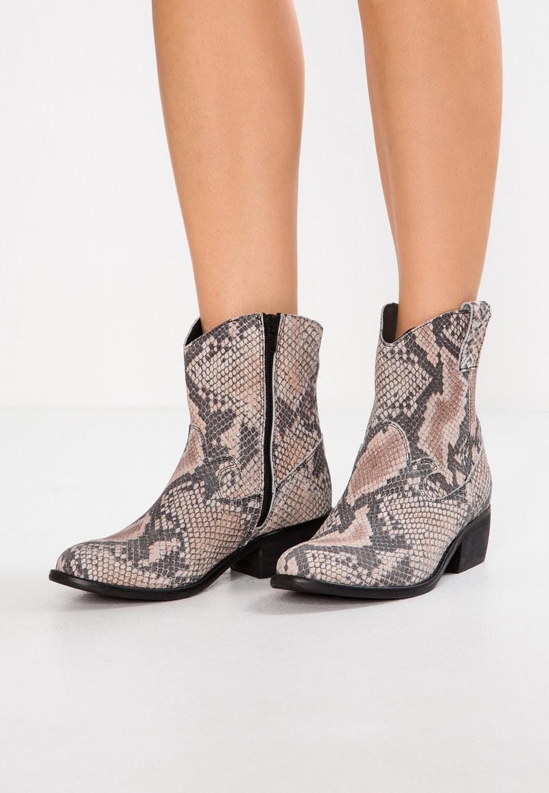 Bottes cheville à imprimé serpent avec un bout pointu, fermeture éclair, et un talon carré bas. Le matériau présente un motif texturé de reptile dans des tons neutres.