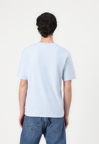 Light blue short-sleeve t-shirt made of soft fabric, with a round neckline and relaxed fit. Features a plain back and slight texture.