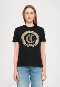 Schwarzes Baumwoll-T-Shirt mit einem großen goldenen runden Logo mit aufwendigen Details in der Mitte. Kurze Ärmel und Rundhalsausschnitt.