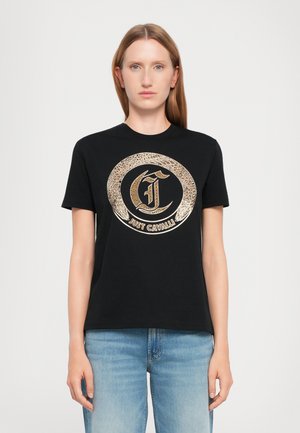 Black cotton t-shirt featuring a large gold circular logo with intricate detailing in the center. Short sleeves and crew neckline.