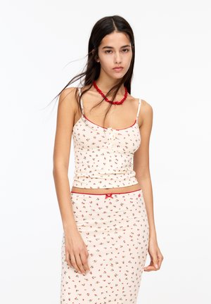 Floral patterned cream tank top and matching skirt with red accents, featuring thin straps and a fitted design.