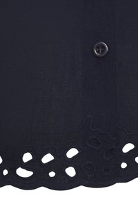 Marineblaues Gewebe mit strukturiertem Finish, ausgestattet mit einem Knopfverschluss und einem dekorativen Wellenrand mit aufwendigen Ausschnittmustern.