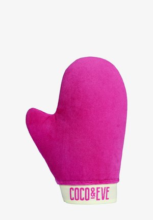 Rosa Bräunungshandschuh mit weicher, samtiger Textur. Verfügt über einen Daumen und einen markengeschützten Riemen aus leichtem Stoff mit dem Schriftzug "COCO & EVE" in fetten Buchstaben.