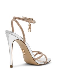 Hoge hakken sandaal met een metalen zilveren hak, beige voetbed en gekruiste banden versierd met heldere rhinestones. Inclusief verstelbare enkelband.