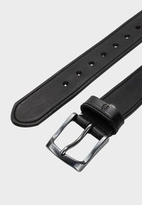 Zwarte leren riem met een zilveren metalen gesp. Heeft een gladde textuur, rechte randen en gelijkmatig verdeelde gaatjes voor aanpassing.