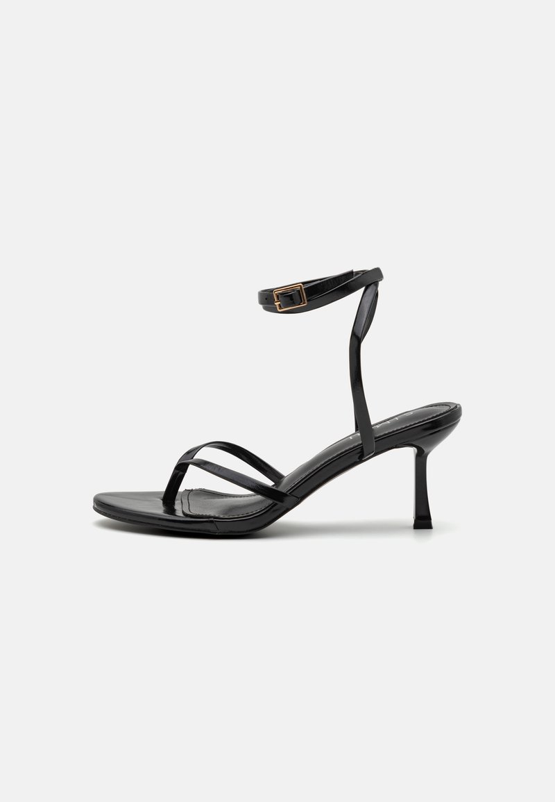 Mustad mustakud jalatsid kitsas rihma kujundusega, siledast materjalist, ankle'i pandla ja terava varbaga. Reguleeritav pahkluu rihma detail.