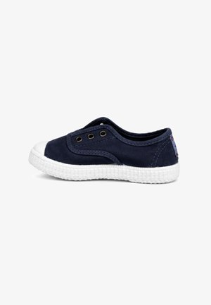 Sneaker slip-on blu navy con suola in gomma bianca e punta, con tre occhielli metallici sul lato per la ventilazione.