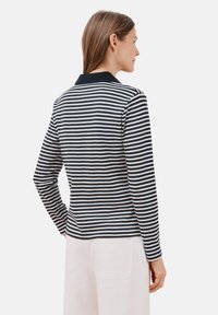 Polo-shirt met lange mouwen in marineblauw en witte strepen, voorzien van een kraag en een textuurstof. De achteraanzicht benadrukt een aansluitende silhoutte.