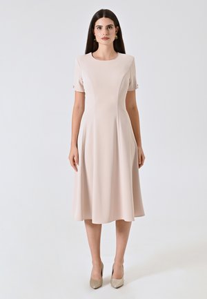 Une robe rose clair jusqu'aux genoux avec des manches courtes, un col rond et une jupe évasée ; tissu texturé avec une finition lisse.