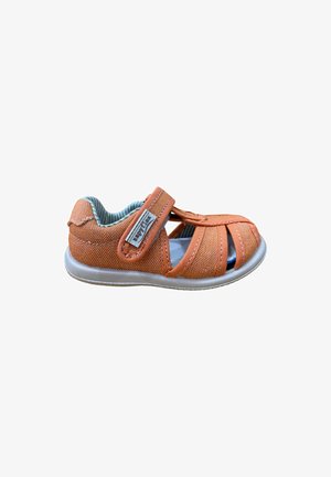 Sandalia para niño pequeño de tela naranja con puntera cerrada, correa de Velcro etiquetada como "Zappylux" y suela de color gris claro sobre fondo blanco.
