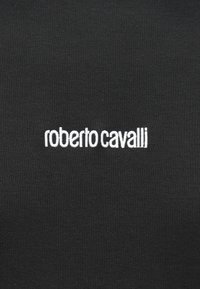Tessuto nero con logo ricamato bianco "roberto cavalli" centrato su di esso.