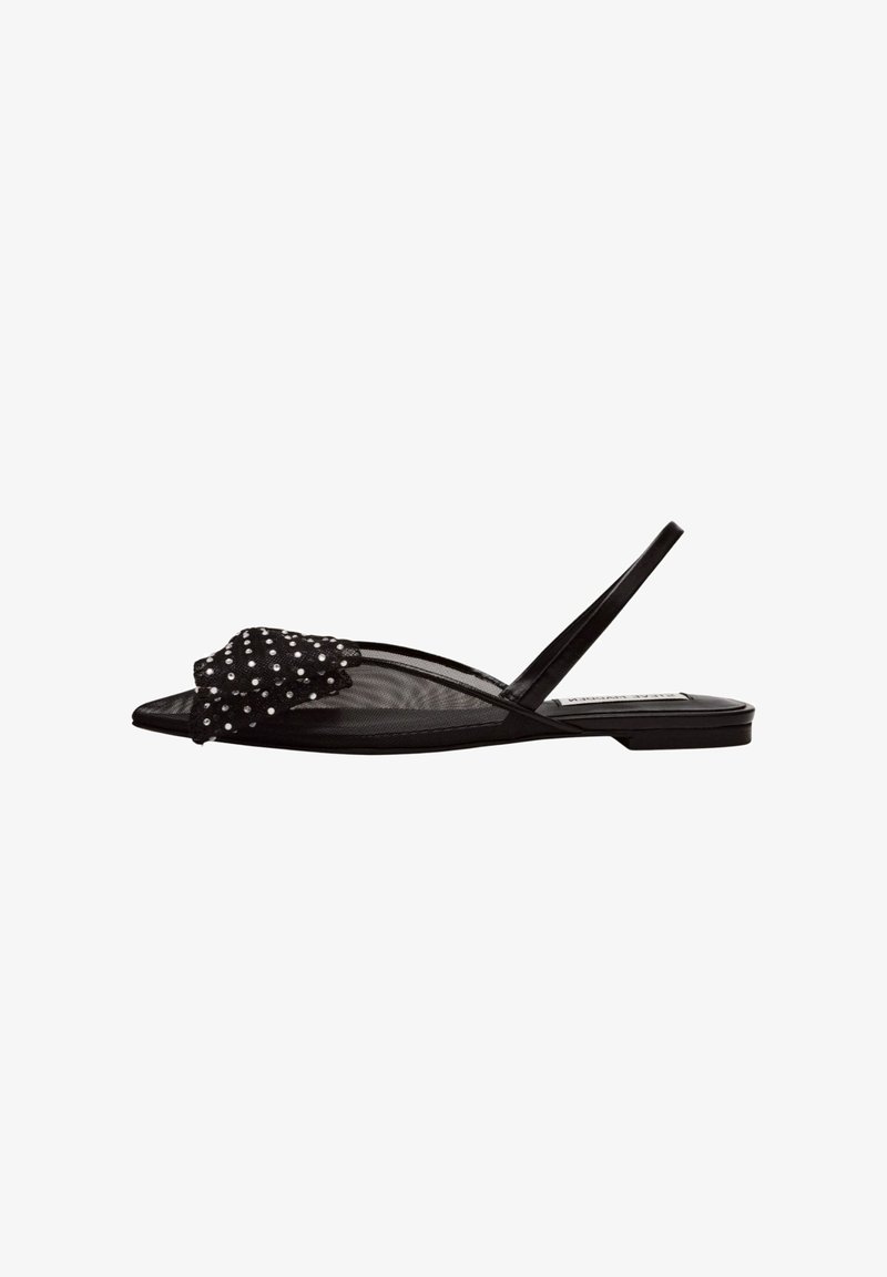 Sandalha preta plana com um upper em malha transparente, decorada com um laço texturizado e bolinhas brancas. Apresenta uma tira slingback e sola plana.