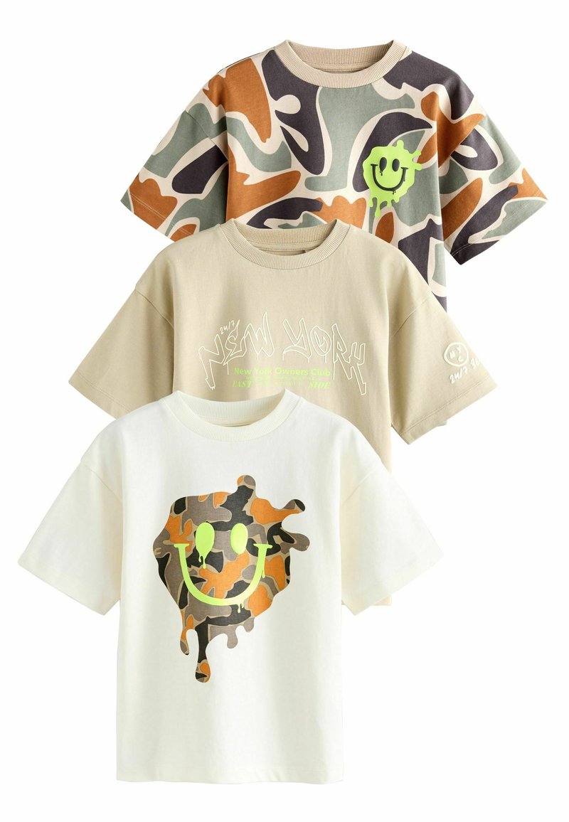Trois t-shirts graphiques : un avec un motif de camouflage abstrait dans des tons terreux, un t-shirt beige avec du texte, et un t-shirt blanc avec un design de smiley coloré.