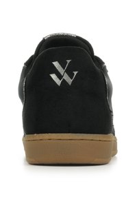 Achteraanzicht van zwarte sneaker met gum zool en witte overlappende "V" en "W" logo op de hieltab tegen een witte achtergrond.