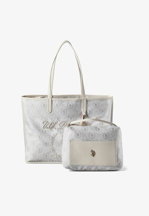 Grand sac fourre-tout blanc avec longues poignées et pochette zippée plus petite assortie, présentant un motif subtil et un emblème doré.