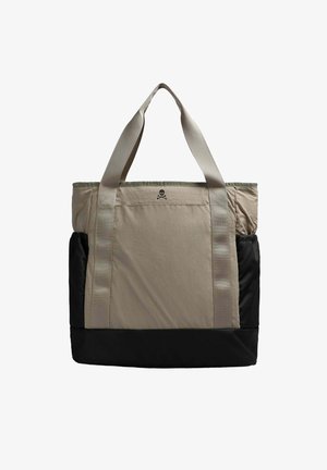 Bolso tote en beige y negro, con un gran compartimento principal, dos asas de transporte y un pequeño logo de calavera en la parte frontal.