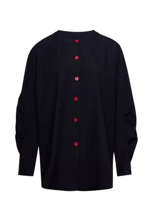 Blouse noire à manches longues avec six boutons rouges brillants sur le devant et un col rond.