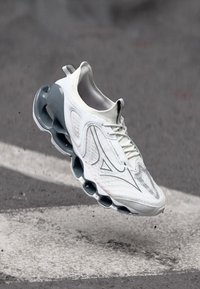 White athletic shoe with a textured upper and pronounced gray sole featuring distinctive bubble-like cushioning elements.