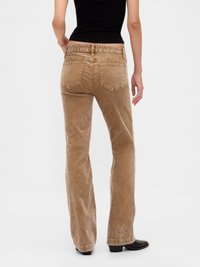 Brown corduroy flared jeans with a high waist, featuring back pockets and a textured finish. Worn with a black fitted top and ankle boots.