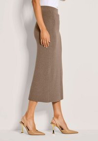 Gebreide bruine midi-rok met een hoge tailleband, aangevuld met beige puntige slingback hakken met gouden hakaccenten.