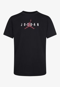 Camiseta de algodón negra con un gran logo rojo "Jumpman" y letras blancas que dicen "JORDAN" en el pecho. Diseño clásico de cuello redondo.