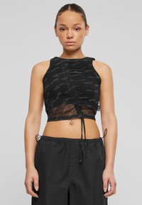 Svart crop top med en gjennomsiktig overlay, med et rynket design og gjentatt logo mønster. Knytes i bunnen og er uten ermer.
