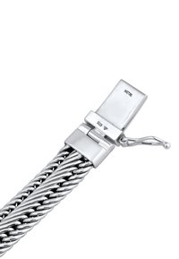 Silverfärgad metallarmband med en tvinnad design, säkert lås och stämplade märkningar för äkthet.