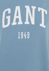 Felpa in cotone azzurro chiaro con grande scritta bianca "GANT" e l'anno "1949" sotto. Texture liscia con vestibilità casual.