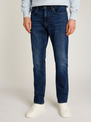 Jeans in denim blu scuro con un taglio dritto, dotati di tasche anteriori, leggero effetto di sfumatura e chiusura con zip. Abbinati a sneaker bianche.