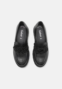 Zwarte leren loafers met een gevlochten kralendetail op de bovenkant. Platte rubberen zool met een ronde neus en een zachte voering. Maat: 4½.