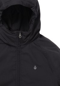 Chaqueta negra con capucha, fabricada en un tejido suave y duradero. Cuenta con un cierre completo y un pequeño logo en el pecho. Diseño simple y funcional.