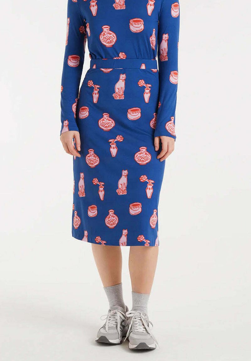 Vestido azul de manga larga con una silueta ajustada, que presenta un patrón rojo y rosa de gatos y jarrones. La tela tiene una textura suave.