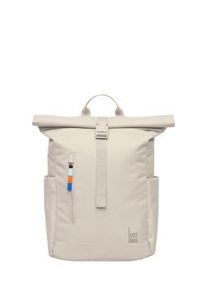 Beżowy plecak z zakładanym na rolkę zamknięciem, przednią kieszenią na suwak, bocznymi kieszeniami, pojedynczym górnym uchwytem oraz logo "GOT BAG" w dolnym prawym rogu.