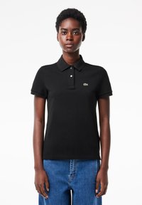 Svart polo-shirt i bomull, med korta ärmar, krage och en tre-knapplång placket. Litet grönt logotyp på bröstet.
