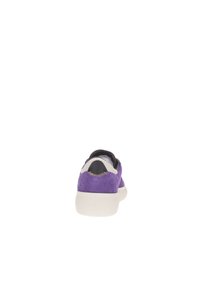 Zapatilla de ante púrpura con suela blanca, capuchón negro en el talón y costuras en contraste en la parte trasera. Diseño minimalista y forma redondeada.