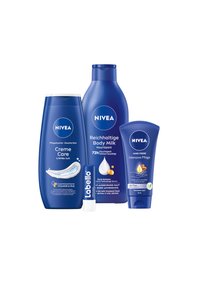 Vier NIVEA Produkte: ein dunkelblaues Duschgel, eine Flasche Körpermilch, eine Lippenbalsam-Tube und eine blaue Handcreme, alle mit Etiketten und Logos versehen.