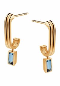 Złote kolczyki o zakrzywionym kształcie, z prostokątnym niebieskim kamieniem zawieszonym na obrączce typu huggie.