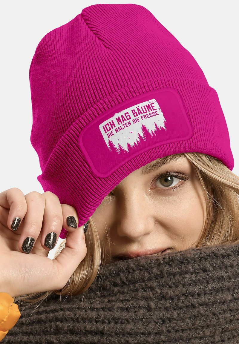 Fuchsia knitted beanie with a folded cuff, featuring a white graphic print stating "Ich mag Bäume" and a forest design on the patch.