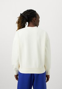 Tejfehér színű pulóver klasszikus nyakkivágással és laza szabással, bordázott mandzsettákkal és szegéllyel. Simaságával jellemző pamut anyag, egyszerű dizájn.