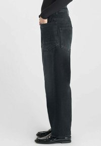 Jean en denim noir taille haute avec une coupe droite, doté de deux poches plaquées à l'arrière et d'une texture lisse.