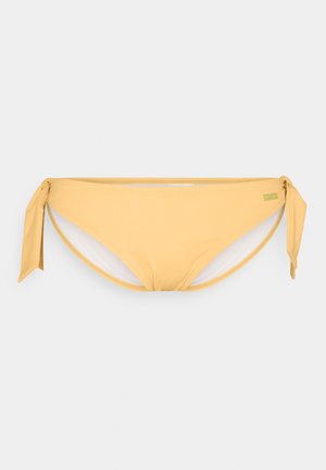 Calção de bikini amarelo com fechos laterais e textura suave. Apresenta um brilho subtil e contrasta com o forro branco interior.