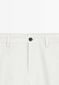 Pantaloni grigio chiaro realizzati in un tessuto testurizzato, con chiusura a bottone nero, passanti per cintura e un design pulito in vita.
