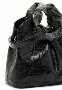 Czarna torebka z sztucznej skóry w wzór krokodylej skóry, z zebranym wierzchem, gładką fakturą i sztywnym kształtem, posiadająca płaskie dno oraz krótką, mocną rączkę.