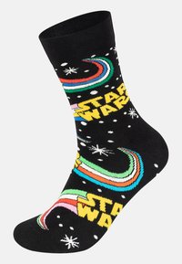 Chaussette noire avec un texte "Star Wars" multicolore, des motifs graphiques tourbillonnants et des détails en flocons de neige blancs. Fabriquée à partir d'un matériau extensible et doux.